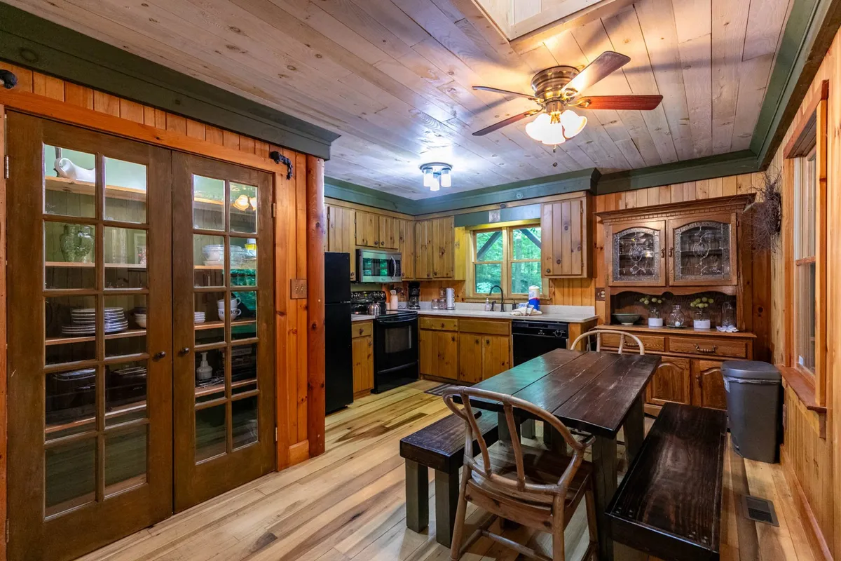 An inviting dining area centered around a wooden table, flanked by glass-front cabinets and a large window that bathes the space in natural light. The setting captures the ambiance of shared meals and togetherness.